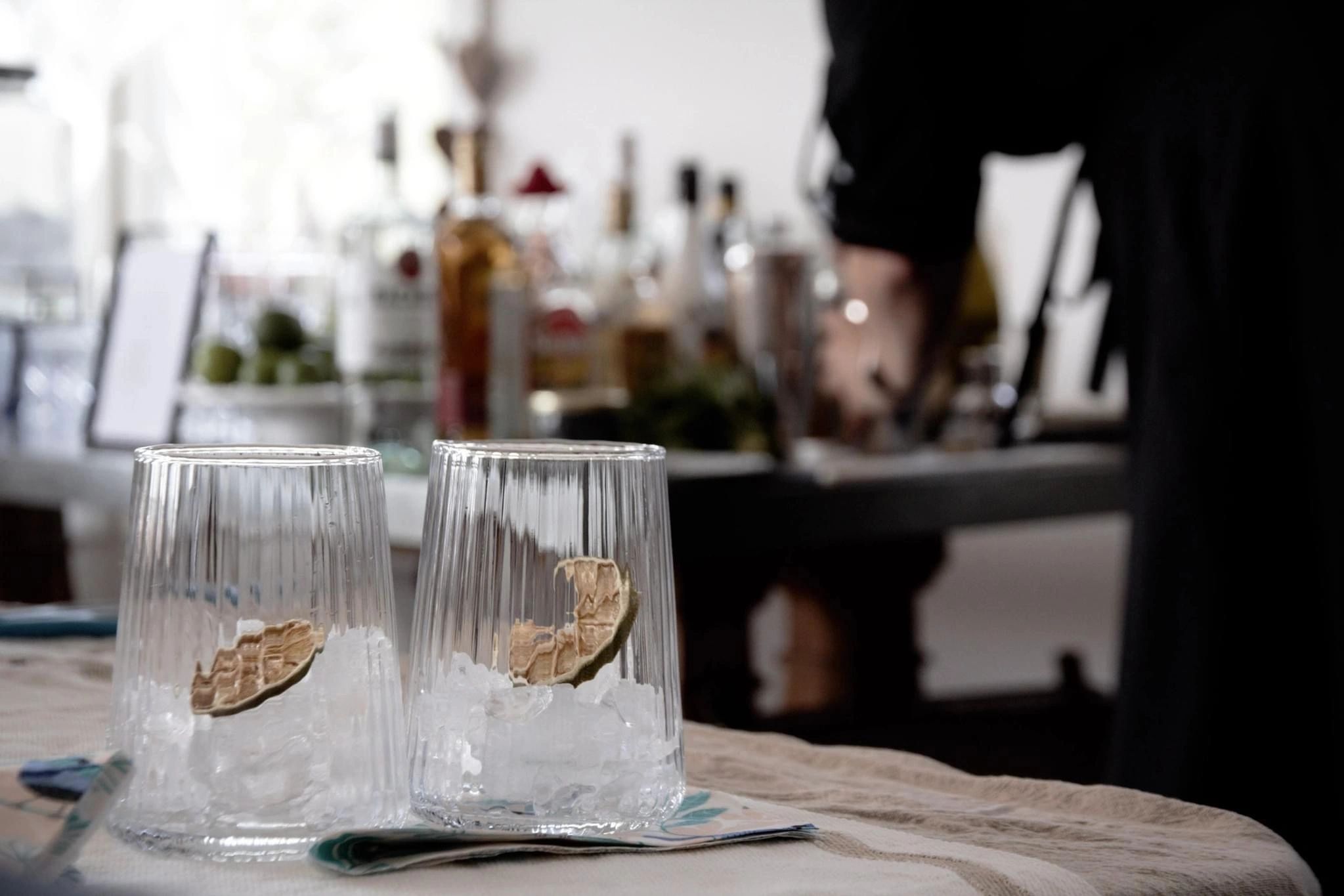 Two glasses filled with ice and dried lime wedges on a table.