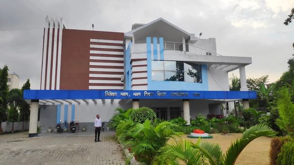 Modern government building with blue and white facade and landscaped garden.