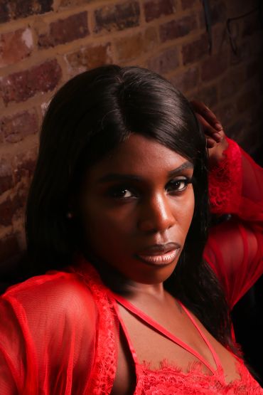 Woman in red lace outfit against brick wall.
