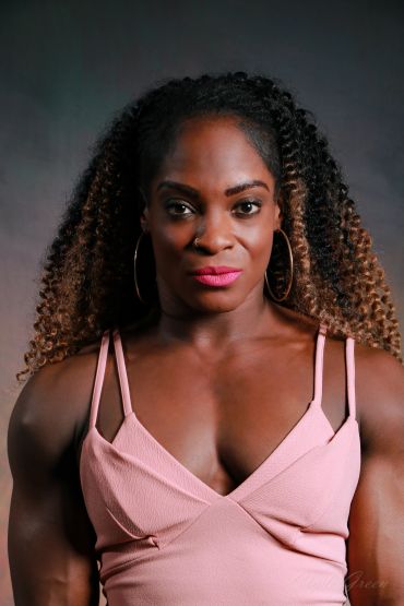 Confident woman with curly hair and pink dress.