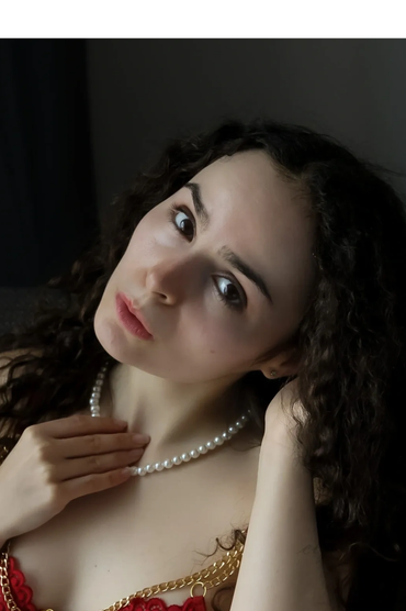 Woman in red lace lingerie with pearl necklace.