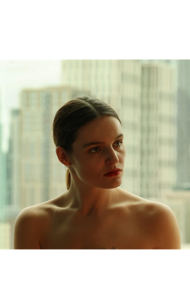 Pensive woman in front of city skyline.