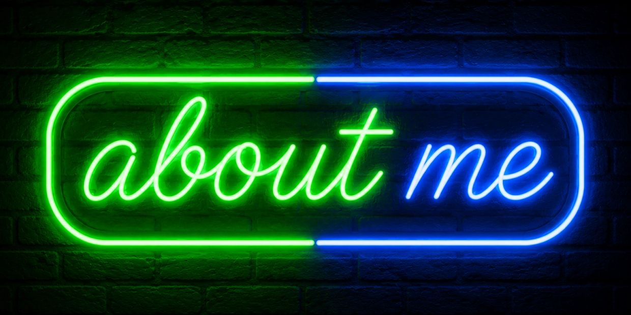Neon sign glowing with words 'about me' in green and blue.