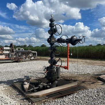 Industrial valve system on a gravel surface under a partly cloudy sky.