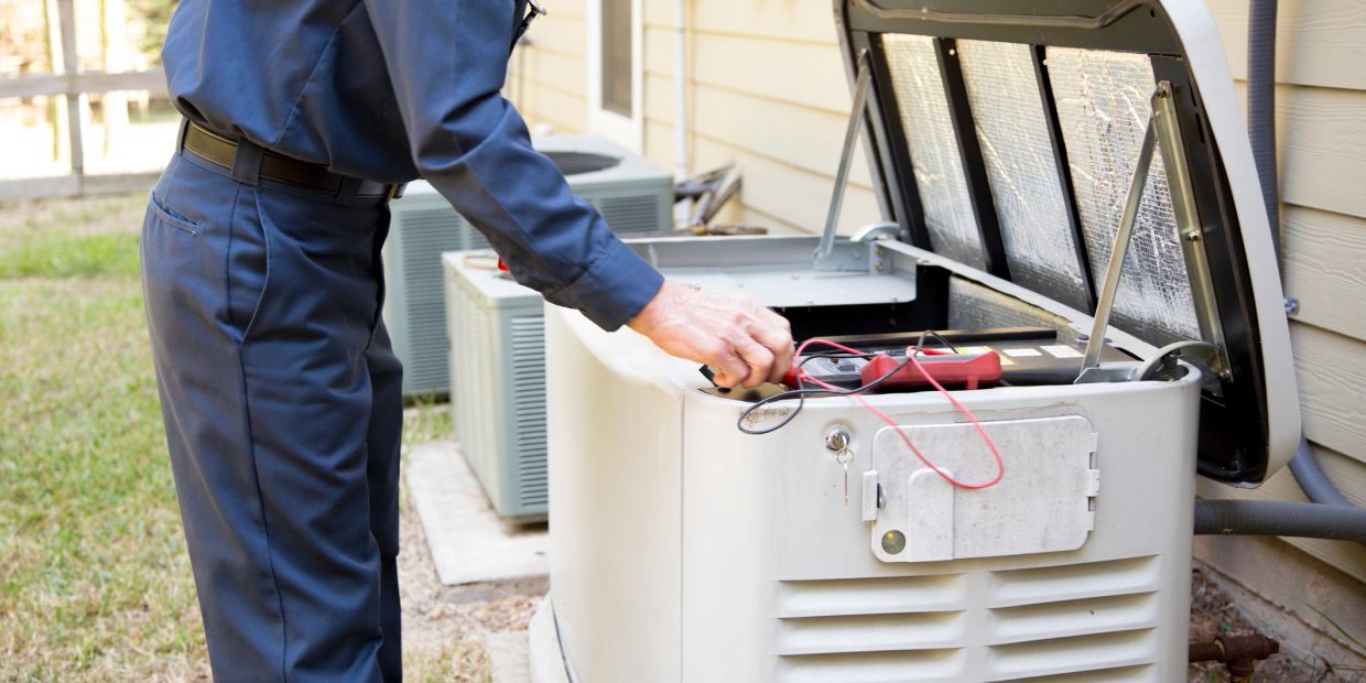Technician inspecting a home backup generator outdoors.