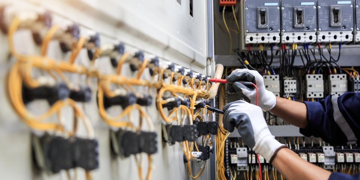 Electrician testing wiring connections in an electrical panel.