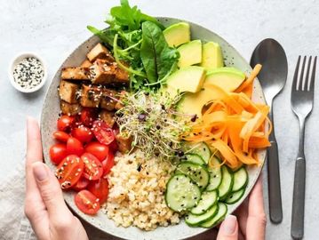 Colorful healthy bowl with vegetables, quinoa, and avocado.