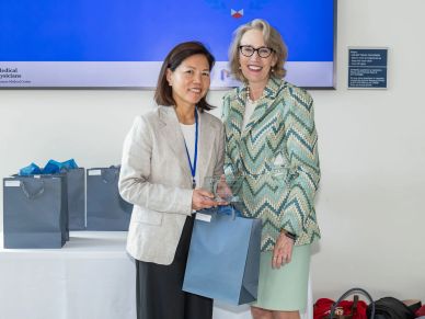 Two women standing together holding awards and gift bags.