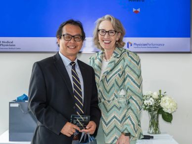 Two professionals smiling at an award ceremony with a blue backdrop.