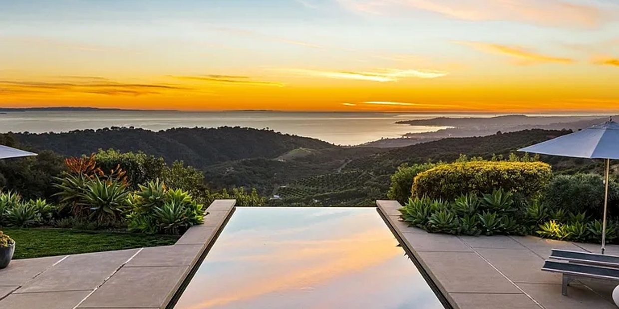 Piscina infinita con vista al atardecer y vegetación.