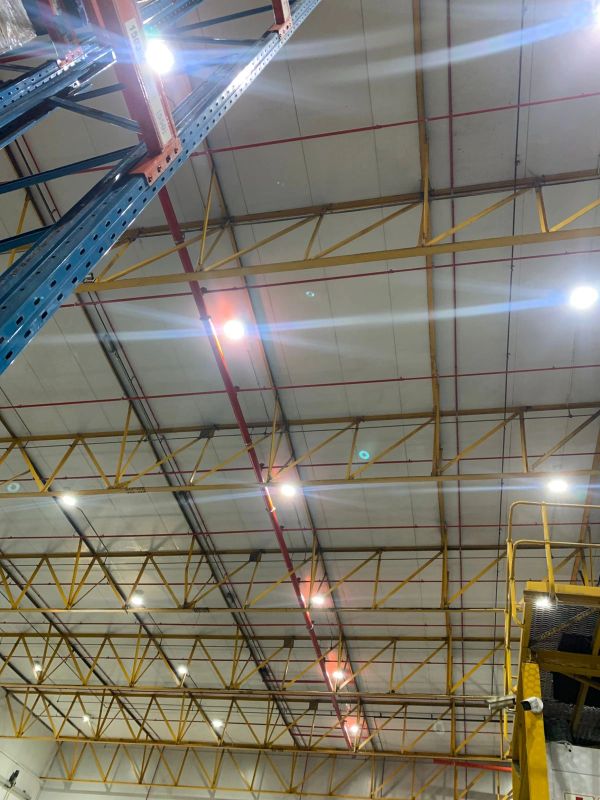 Ceiling with yellow metal framework and bright lights.