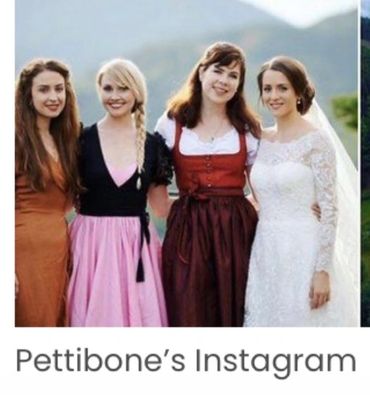 Four women in dresses posing outdoors, one in a wedding gown.