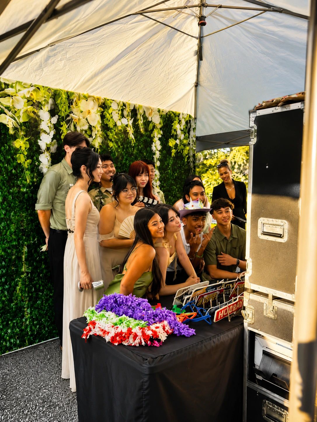 Group of friends posing happily in a photo booth at a decorated outdoor event.