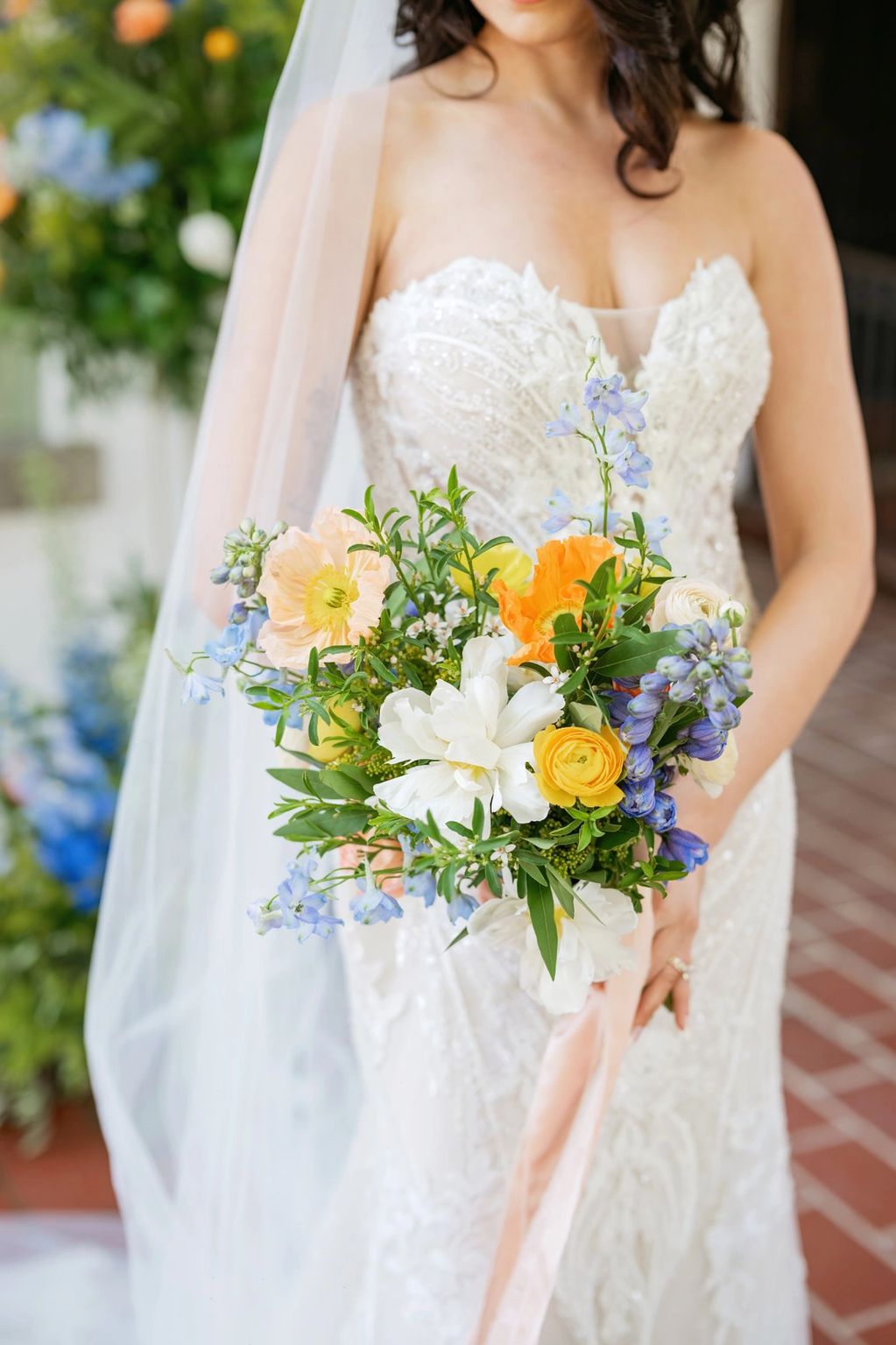 colorful bridal bouqet in front of wedding dress