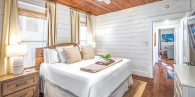 Bright bedroom with wooden ceiling and white walls.