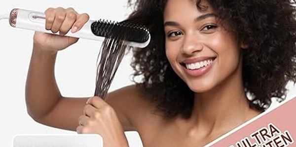 Smiling woman styling curly hair with a heated round brush.