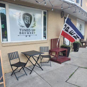 Outdoor seating at Tuned Up Brewery with a flag and string lights.