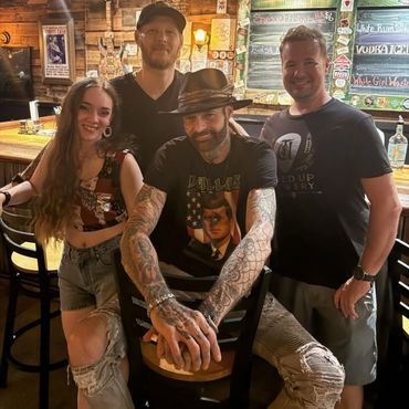 Four friends posing in a rustic bar with wooden decor.
