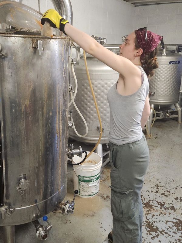 Woman working with brewing equipment in a brewery.