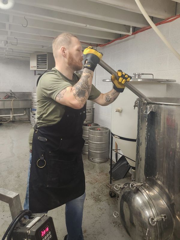 Man brewing beer in a brewery using large equipment.