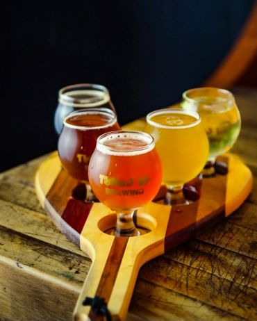 Flight of craft beers on a wooden paddle.