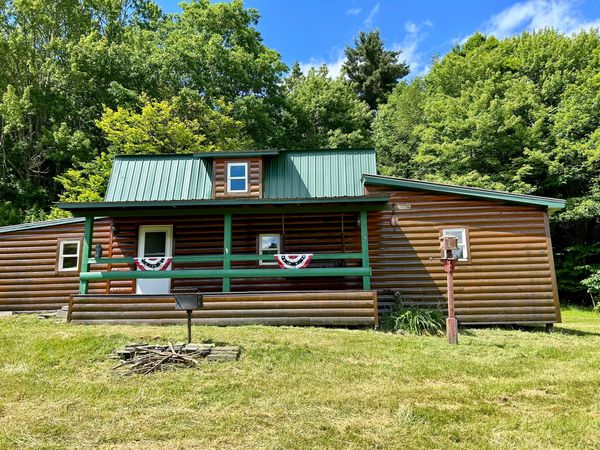 Log cabin with green roof in a grassy area.