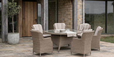 Outdoor patio set with wicker chairs and a round glass table.