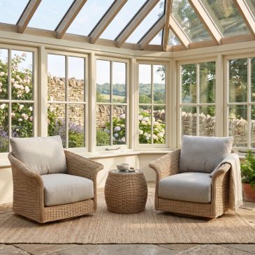 Cozy sunroom with two wicker armchairs and a small table.