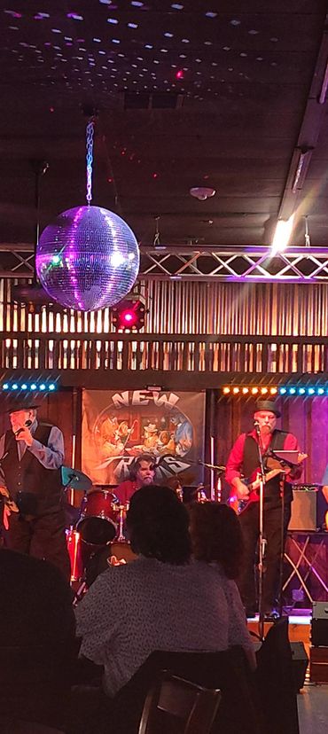 A band performs on stage under a disco ball in a lively venue.