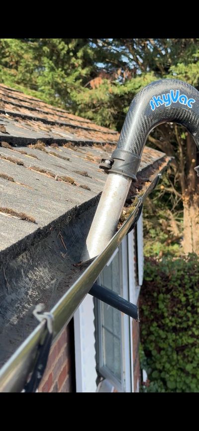 SkyVac gutter cleaning vacuum tube positioned in a rain gutter on a roof.