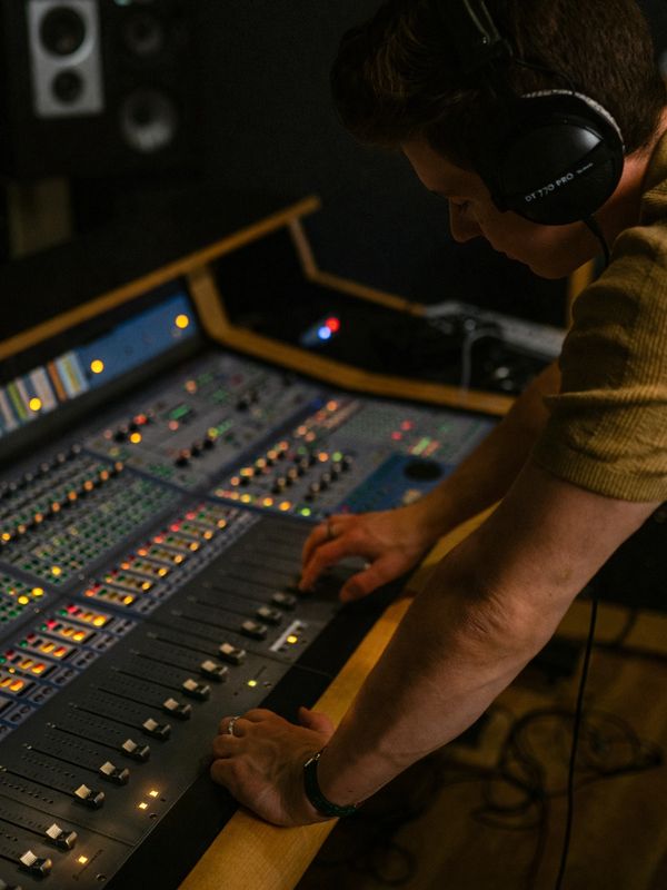 Person adjusting controls on an audio mixing console.