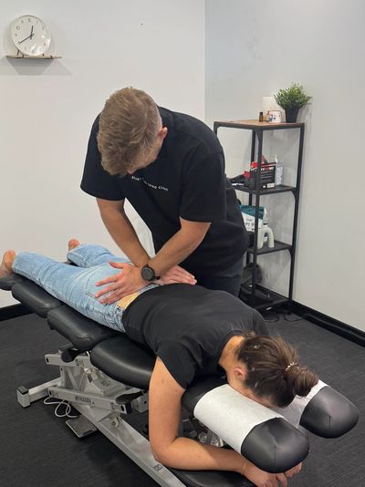 Chiropractor adjusting a patient's back on a treatment table.