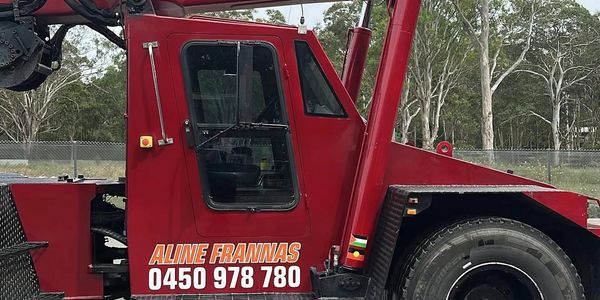 Red crane truck with 'ALINE FRANNAS' and contact number displayed.