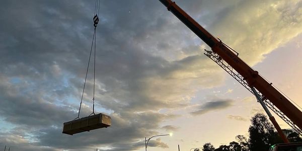 Crane lifting a large package against a dramatic cloudy sky at dusk.