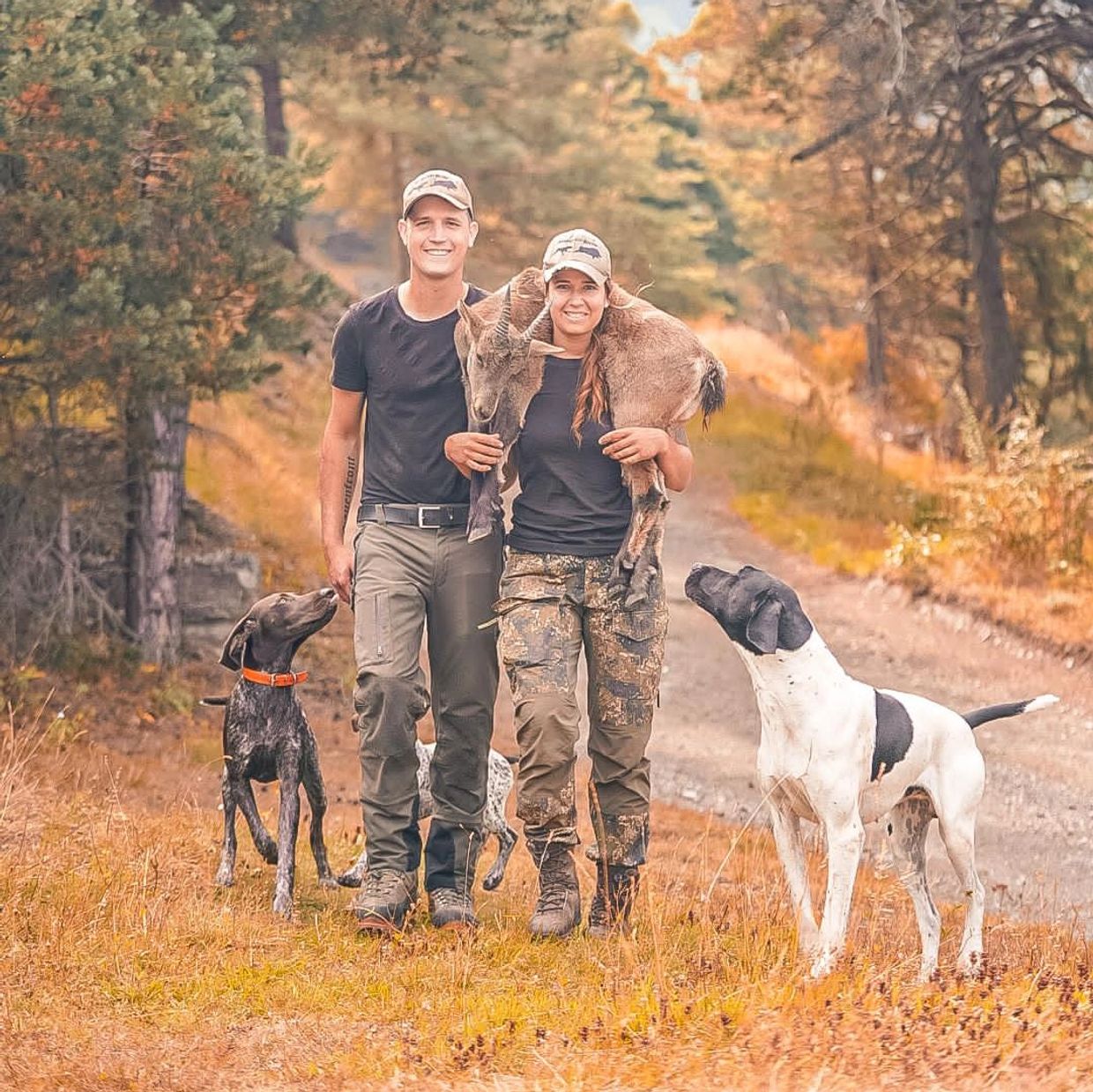 Paar in der Natur mit Ziegenbaby und Hunden.