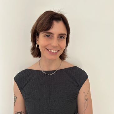 Smiling woman with short hair and tattoos.