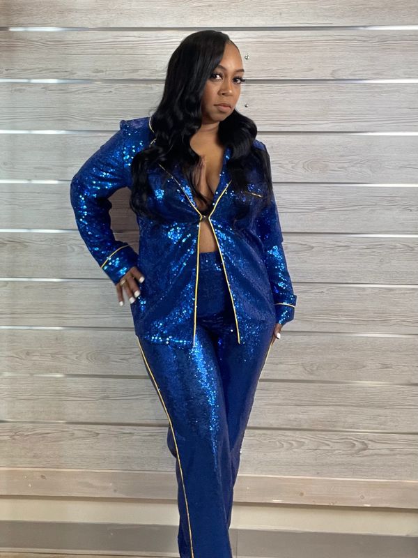 Woman wearing a shiny blue sequin outfit with gold trim, posing confidently indoors.