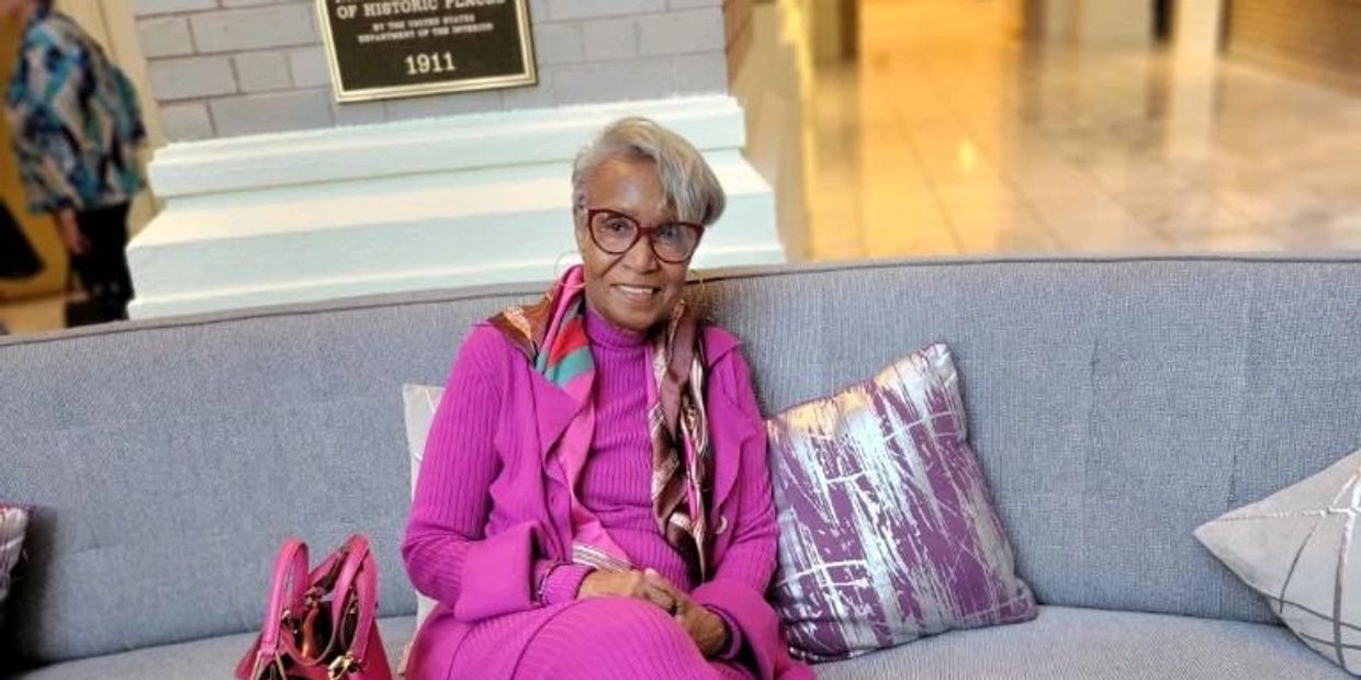 Elegant woman in a vibrant pink outfit sitting on a couch with matching accessories.
