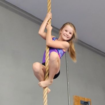 Young girl climbing a rope in the Tuscola Youth Gymnastics gym