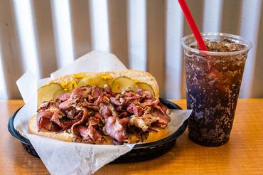 pastrami on french roll sandwich with large Coke