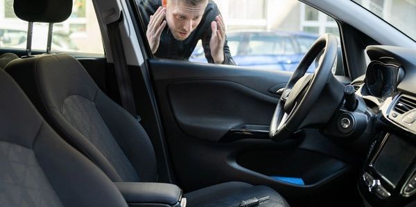 Man frustrated outside car with keys left inside on the seat.