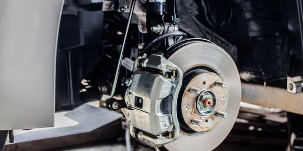 Close-up of a car's brake disc and caliper without the wheel.