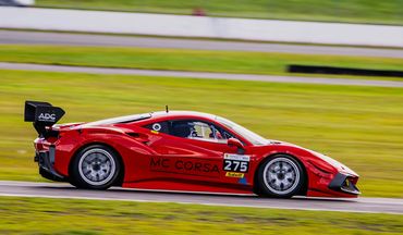 Red race car speeding on a track during a race event.