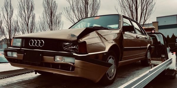 Badly damaged car with front-end collision damage being removed by a tow truck in Abbotsford, BC.