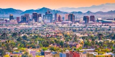 City skyline with mountains in the background at sunset.
