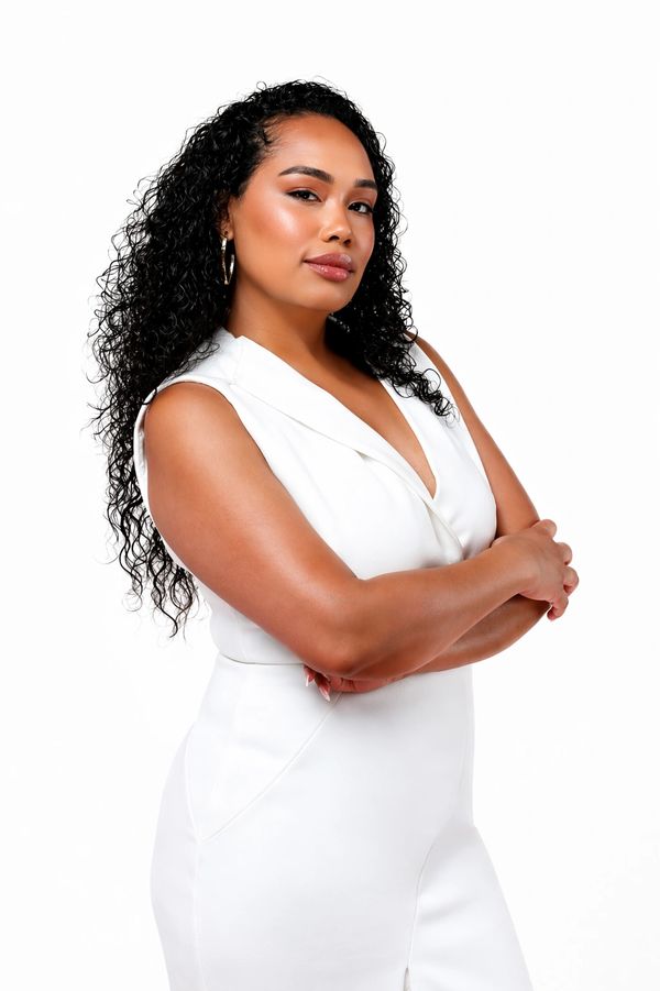 Confident woman in a white outfit with arms crossed.
