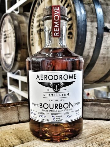 Aerodrome Distilling bourbon bottle on wooden barrels.