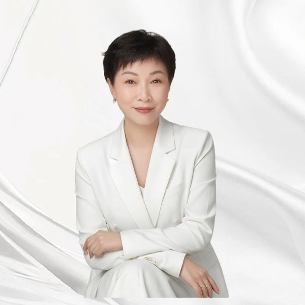 Confident woman in a white suit against a silky white background.