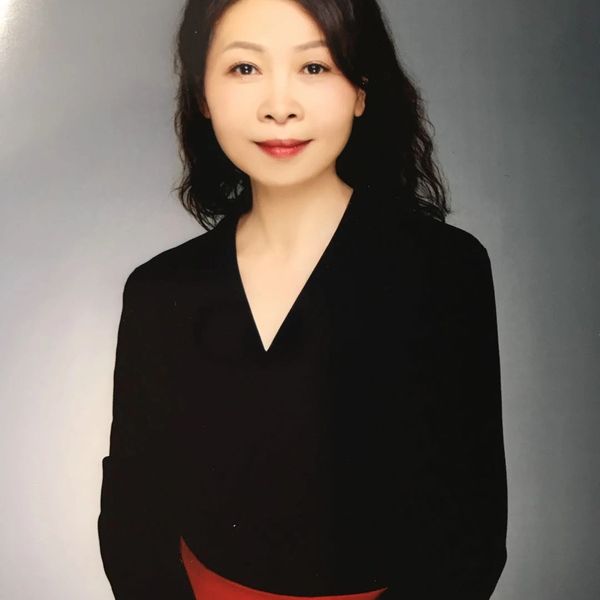 Professional woman in black attire posing against a neutral background.