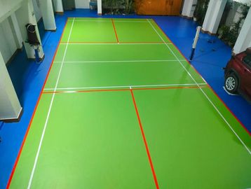 Indoor badminton court with green flooring and red-white boundary lines.